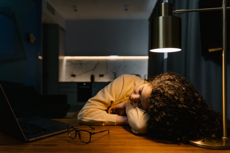 Tired woman rubbing eyes while working on computer screen, showing signs of digital eye strain in office environment